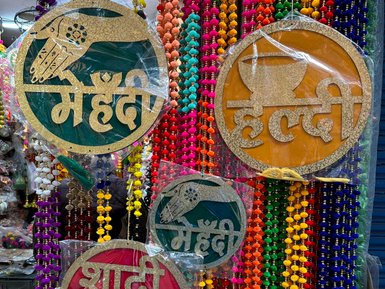 Bunte Dekorationen mit goldenen Schildern, die Hochzeits- und Festtagsbotschaften in Hindi zeigen, umgeben von farbigen Perlen.