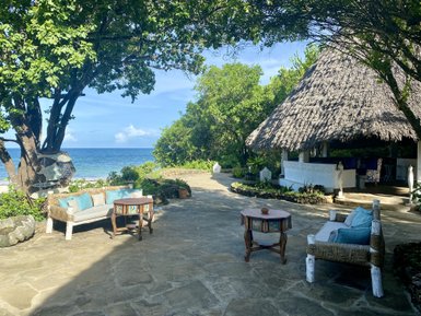 Ein einladender Außenbereich mit einem gemütlichen Sofa und einem Tisch, umgeben von üppigem Grün und Blick auf das Meer.