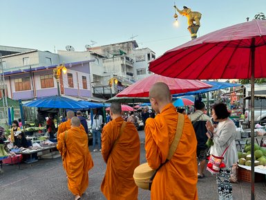 Mönche gehen über Markt in Uthai Thani in orangenen Gewändern - Thailand Familienreise