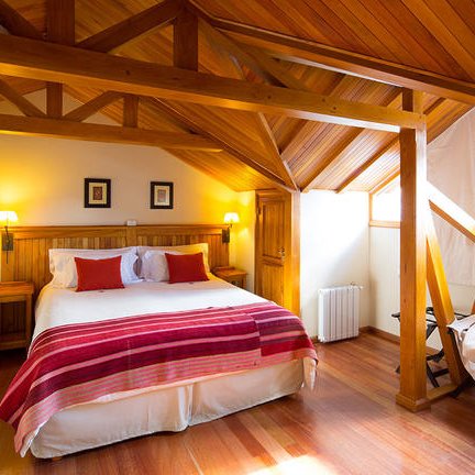 Ein gemütliches Schlafzimmer mit einem großen Bett, Holzdecke und warmem Licht, das eine einladende Atmosphäre schafft.