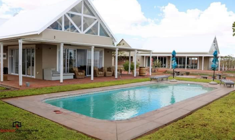 Poolbereich der Africa Safari Lodge mit moderner Architektur und Chalets im Hintergrund.