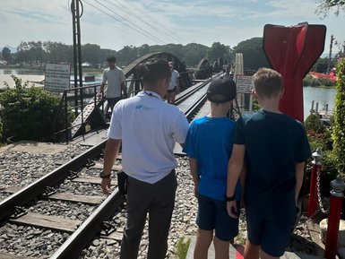 Guide zeigt Touristen die berühmte Brücke am River Kwai - Thailand mit Kindern
