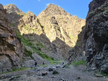 Wanderer durch die schmale Geierschlucht, umgeben von steilen, felsigen Wänden und üppigem Grün in der Umgebung.