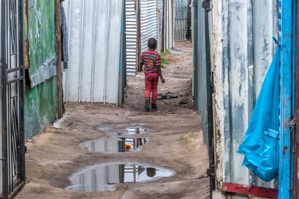 Kind läuft durch ein einfaches Wohnviertel – Südafrika Reise mit Kindern