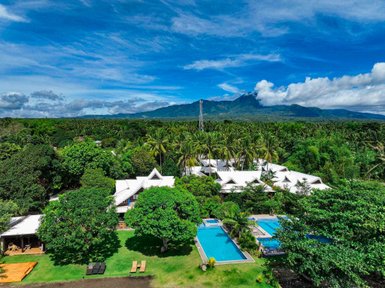 Eine expansive Aussicht auf ein tropisches Resort mit weißen Dächern, Pools und üppigem grünem Garten.