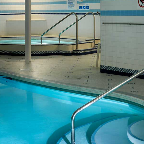 Ein eleganter Poolbereich mit klarem Wasser und einem Whirlpool, umgeben von hellen Fliesen und einem modernen Design.