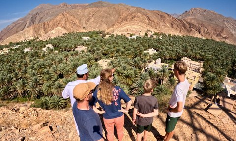 Einheimischer führt eine Familie durch das traditionelle Lehmdorf Birkat Al Mauz – Oman Reise mit Kindern