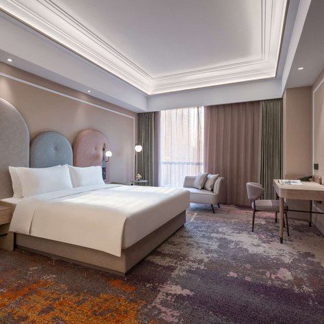 Ein modernes Hotelzimmer mit einem großen Bett, eleganten Wänden und einem gemütlichen Sessel in der Ecke.