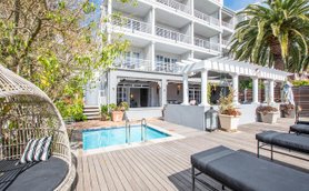 Ein eleganter Außenbereich mit einem kleinen Pool, umgeben von modernen Liegen und üppigem Grün.