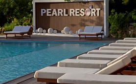 Ein einladender Poolbereich im Pearl Resort, umgeben von Liegen und einer stilvollen Wand mit dem Resort-Namen.