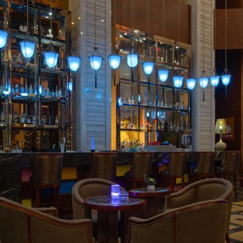 Elegante Bar mit blauen Lampen, einer stilvollen Theke und gemütlichen Sitzgelegenheiten, die eine einladende Atmosphäre schaffen.