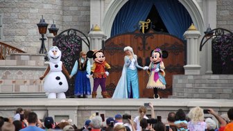 Eine Gruppe von Disney-Charakteren, darunter Elsa und Mickey Mouse, steht auf einer Bühne im Magic Kingdom.