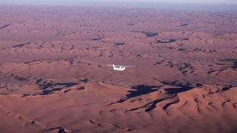Eine Propellermaschine fliegt über die weite Wüste - Namibia mit Kindern