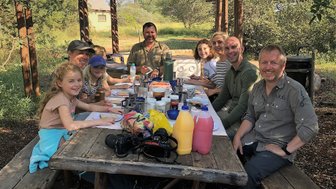 Eine Familie lächelt beim Essen in die Kamera im Makutsi Game Reserve – Südafrika mit Kindern