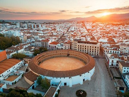 Die Arena von Ronda erhebt sich majestätisch über die Stadt, während die Sonne hinter den Bergen untergeht.