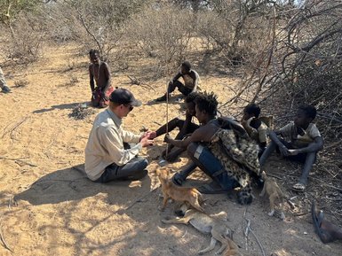 Besucher übt traditionelle Feuertechnik mit dem Hadzabe-Stamm – Tansania Reise mit Kindern
