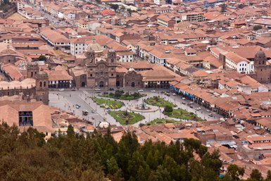 Eine Luftaufnahme von Cusco zeigt die beeindruckende Plaza de Armas mit historischen Gebäuden und lebhaften Grünflächen.