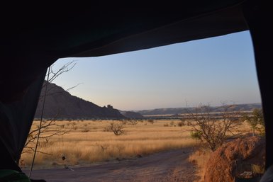 Der Ausblick aus einem Dachzeltfenster auf eine Graslandschaft - Namibia mit Jugendlichen
