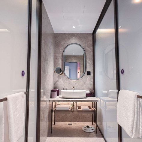 Ein modernes Badezimmer mit eleganten, grauen Wänden und einem ovalen Spiegel über einem stilvollen Waschbecken.