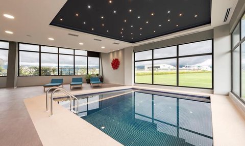 Ein eleganter Innenpool mit blauen Fliesen, umgeben von großen Fenstern, die einen Blick auf die Landschaft bieten.