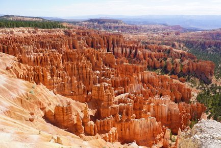 Die beeindruckenden, orangefarbenen Felsformationen des Bryce Canyon erstrecken sich unter einem klaren blauen Himmel.
