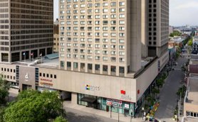 Ein modernes Hotelgebäude mit großen Fenstern und einem klaren, strukturierten Design in der Innenstadt von Montreal.