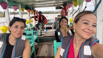Frauen fahren in einem traditionellen Boot auf dem Fluss – Vietnam mit Kindern