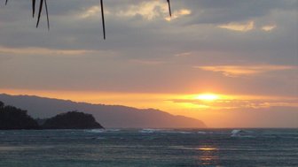 Ein atemberaubender Sonnenuntergang über dem ruhigen Wasser, mit sanften Wellen und einem bewölkten Himmel im Hintergrund.