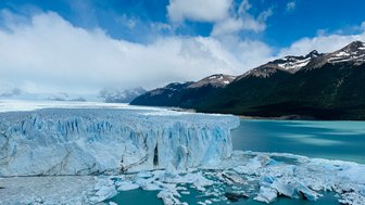 Der Perito Moreno Gletscher erstreckt sich majestätisch über das türkisfarbene Wasser, umgeben von schneebedeckten Bergen.