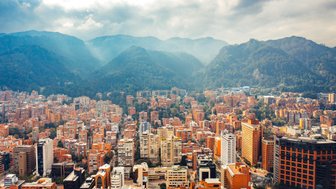 Eine weite Aussicht auf Bogotá, umgeben von majestätischen Bergen, mit einer Vielzahl von orangefarbenen Gebäuden im Vordergrund.