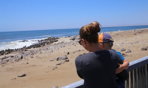 Eine Mutter beobachtet mit ihrem Kind Seehunde am Ufer - Namibia Rundreise mit Kindern