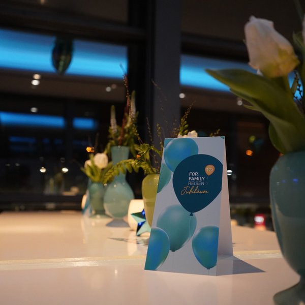 Ein eleganter Tisch mit einer festlichen Karte und frischen Blumen in blauen Vasen, die eine feierliche Atmosphäre schaffen.