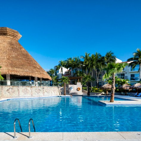 Ein einladender Pool mit klarem Wasser, umgeben von Palmen und einem strohgedeckten Pavillon im Hintergrund.