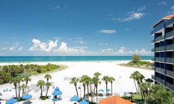Ein atemberaubender Blick auf den weißen Sandstrand und das türkisfarbene Wasser unter einem strahlend blauen Himmel.