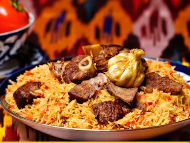 Ein Teller mit duftendem Plov, der mit zartem Fleisch und aromatischem Reis garniert ist, vor einem bunten Hintergrund.