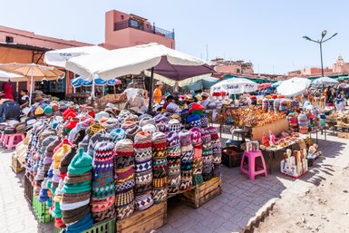 Farbenfrohe Marktstände mit vielfältigen Waren auf dem Djemaa el Fna Platz in Marrakesch – Marokko Reise mit Kindern