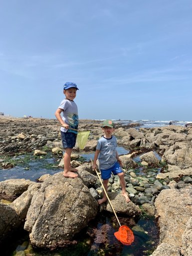 Zwei Kinder spielen zwischen Felsen am Strand - Namibia mit Jugendlichen