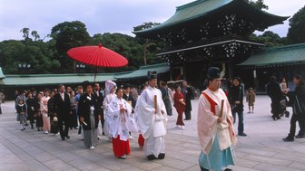 Eine Hochzeitszeremonie im Meiji-Schrein, mit einer Gruppe von Menschen in traditioneller Kleidung, die einen festlichen Umzug machen.