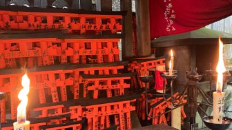 Ein Altar mit brennenden Kerzen und leuchtend orangefarbenen Torii, die für Glück und Wohlstand stehen.