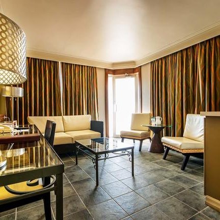 Ein elegantes Hotelzimmer mit modernen Möbeln, großen Fenstern und bunten Vorhängen, das einladend wirkt.