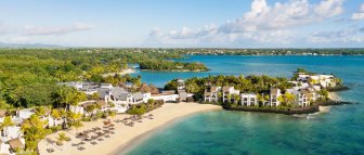 Ein atemberaubender Blick auf das luxuriöse Resort am Strand, umgeben von üppigem Grün und klarem, blauem Wasser.