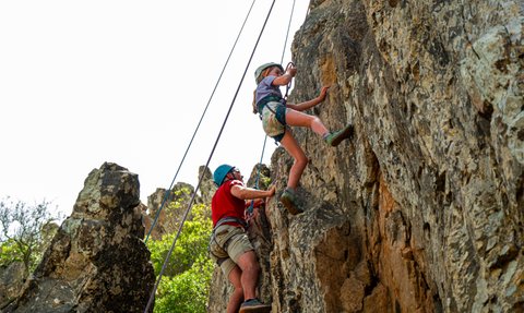 Zwei Personen klettern einen steilen Felsen hoch