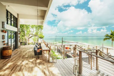 Eine großzügige Terrasse mit Holzbohlen bietet einen herrlichen Blick auf das glitzernde Wasser und den blauen Himmel.