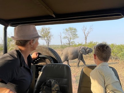 Mutter und Sohn sitzen im Safari-Jeep und beobachten gemeinsam Tiere in der Savanne – Südafrika Familienreise