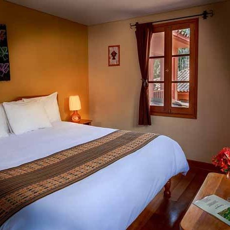 Ein gemütliches Hotelzimmer mit einem großen Bett, dekoriert mit einer bunten Bettdecke und einem Nachttisch mit einer Lampe.