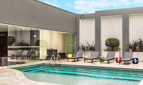 Ein moderner Poolbereich mit Liegen und bunten Schwimmreifen, umgeben von stilvollem, minimalistischem Design.