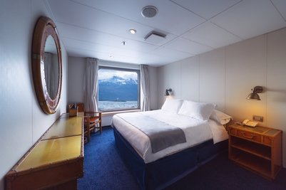 Ein gemütliches Schlafzimmer mit einem großen Fenster, das einen Blick auf schneebedeckte Berge und Wasser bietet.