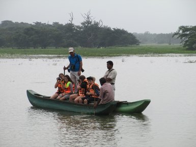 Kinder sitzen auf einem traditionellen Katamaran auf einem Fluss – Sri Lanka Reise mit Kindern