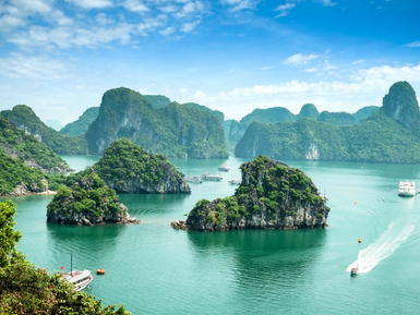 Eine atemberaubende Aussicht auf die smaragdgrünen Gewässer von Ha Long Bay, umgeben von üppigen, bewaldeten Felsen.