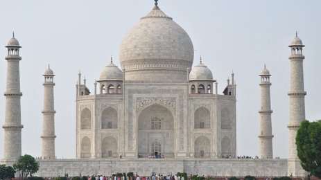 Das majestätische Taj Mahal erhebt sich mit seinen hohen Minaretten und der beeindruckenden Kuppel vor einem klaren Himmel.